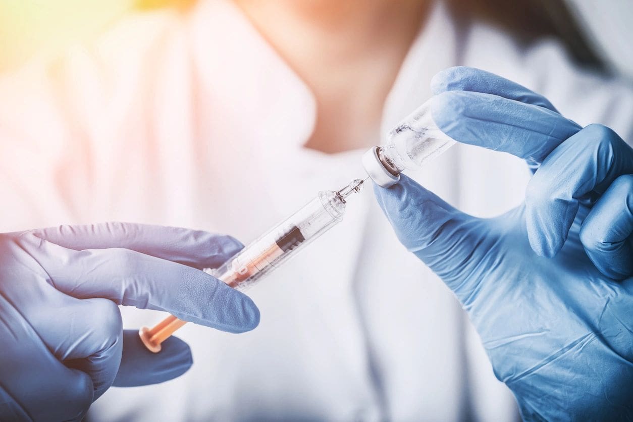 Gloved hands preparing an injectable treatment